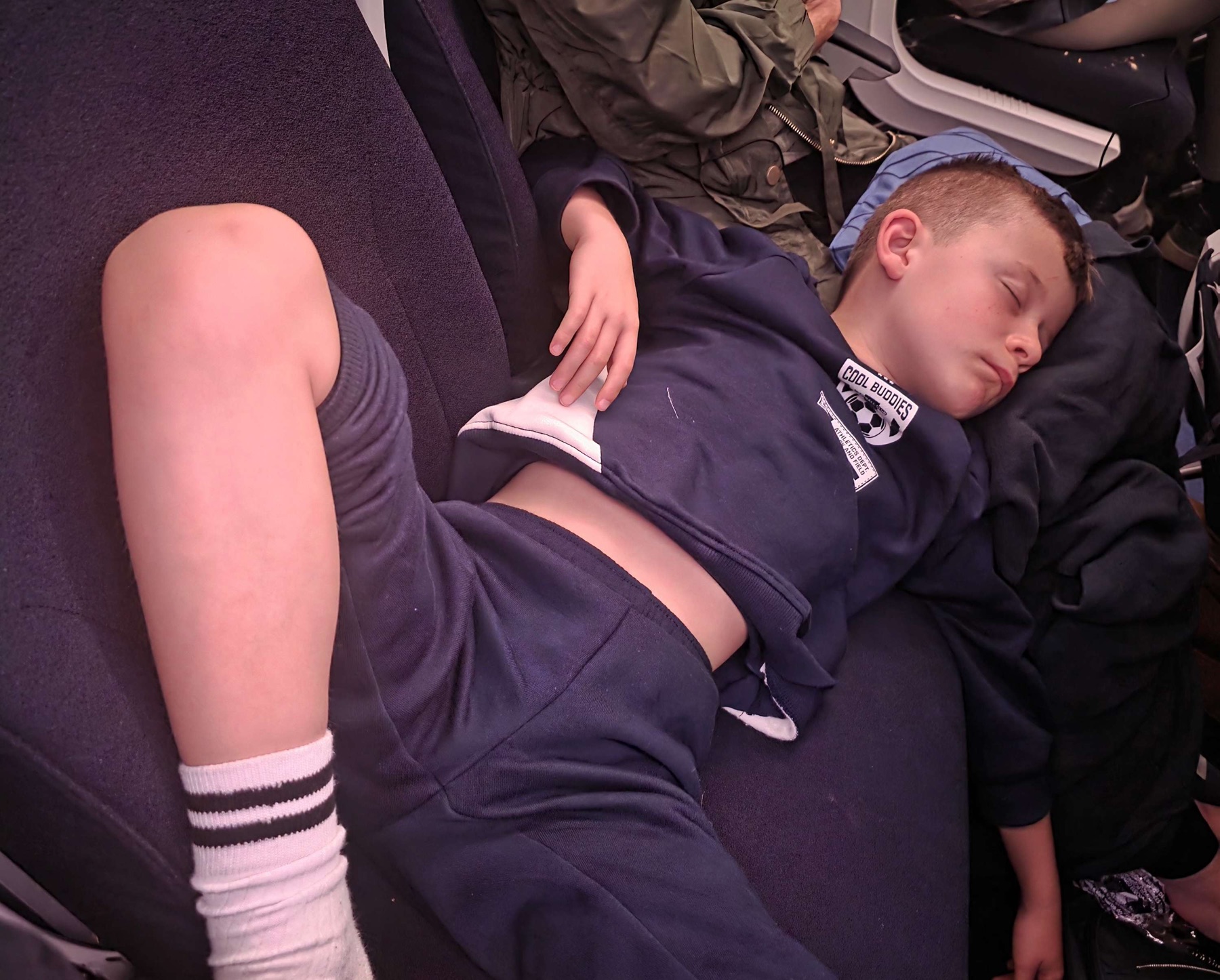 A child asleep across aeroplane seats during the flight.